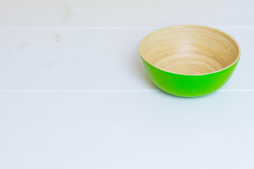 Bamboo green plate on white wooden table, side view, copyspace