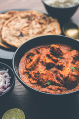 Murgh Makhani / Butter chicken tikka masala served with roti / Paratha and plain rice along with onion salad. selective focus