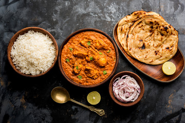 Murgh Makhani / Butter chicken tikka masala served with roti / Paratha and plain rice along with onion salad. selective focus
