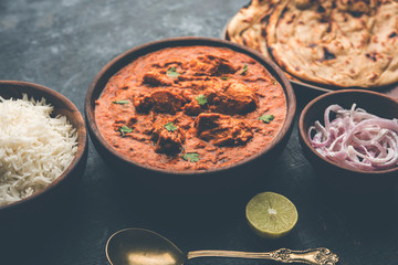 Murgh Makhani / Butter chicken tikka masala served with roti / Paratha and plain rice along with onion salad. selective focus