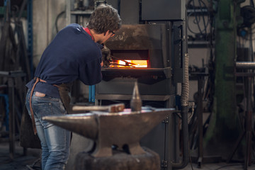 Young blaksmith working in a metalworking workshop