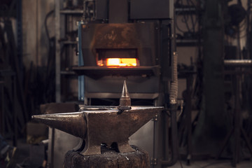 Mallet and tongs on an anvil in front of a furnace