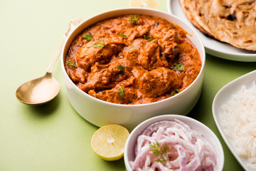 Murgh Makhani / Butter chicken tikka masala served with roti / Paratha and plain rice along with onion salad. selective focus