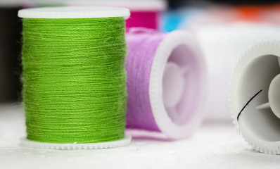 The roll of thread put at the left side on background,green thread,needlework,craft,sewing and tailoring concept,blurry light around