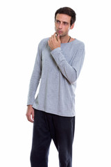 Fototapeta premium Studio shot of young handsome man standing and thinking while lo