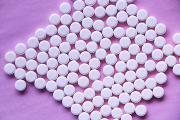 small white pills on a pink background. vitamins, drugs, antibiotics in the form of pills on a textural surface.