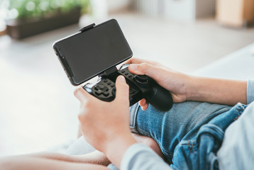 Child hands with game controller connected with smartphone. Electronic devices and technology concept