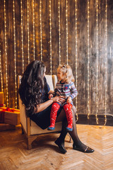 Portrait of beautiful mother and dauther near the Christmas tree. Family woman with little child in a festive New Year's atmosphere. Happy holiday moment.