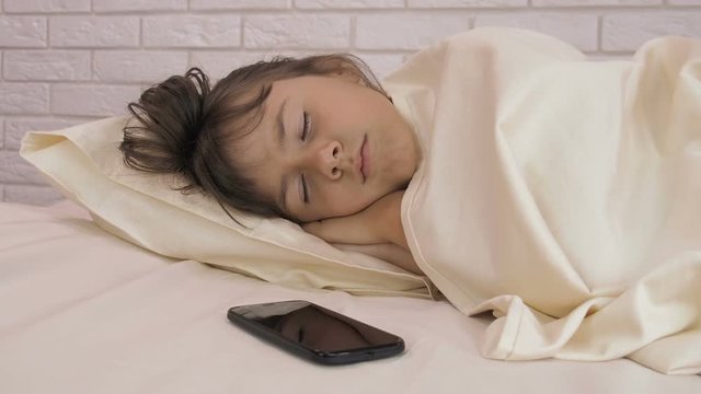The child is sleeping with the phone. Sleeping girl with a mobile phone.