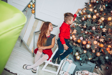 Happy little kids decorate Christmas tree in beautiful living room, Funny christmas moment. Children opening presents on Christmas eve. Holiday gifts for kid.