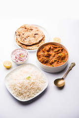 Murgh Makhani / Butter chicken tikka masala served with roti / Paratha and plain rice along with onion salad. selective focus