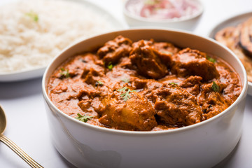 Murgh Makhani / Butter chicken tikka masala served with roti / Paratha and plain rice along with onion salad. selective focus
