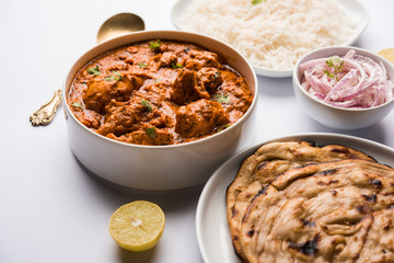 Murgh Makhani / Butter chicken tikka masala served with roti / Paratha and plain rice along with onion salad. selective focus