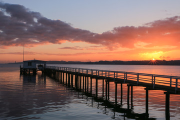 Fototapeta na wymiar malerischer Sonnenuntergang und dramatische Wolken an einer schönen Seebrücke