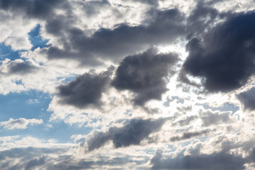 Blue sky with white storm laden clouds tinged with grey  - cumulus