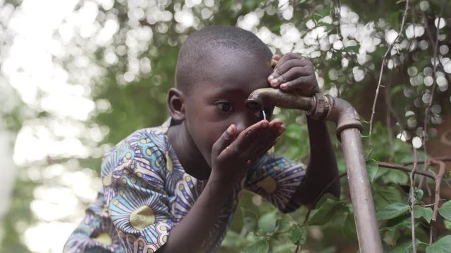 Hands cupped under water tap. An African black boy drinks from a tap some clean, fresh water. 4K RAW clip, please modify and edit (color grade, stabilize, etc.) in postproduction.
