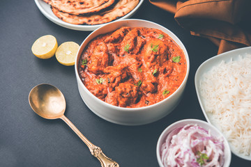 Murgh Makhani / Butter chicken tikka masala served with roti / Paratha and plain rice along with onion salad. selective focus