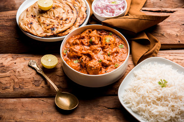 Murgh Makhani / Butter chicken tikka masala served with roti / Paratha and plain rice along with onion salad. selective focus