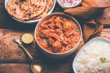 Murgh Makhani / Butter chicken tikka masala served with roti / Paratha and plain rice along with onion salad. selective focus