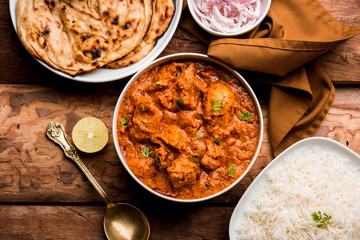 Murgh Makhani / Butter chicken tikka masala served with roti / Paratha and plain rice along with onion salad. selective focus