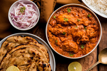 Murgh Makhani / Butter chicken tikka masala served with roti / Paratha and plain rice along with onion salad. selective focus