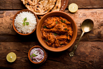Murgh Makhani / Butter chicken tikka masala served with roti / Paratha and plain rice along with onion salad. selective focus
