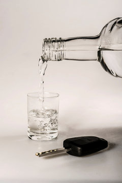 The concept of driving under the influence of alcohol - car keys, a glass and a bottle of alcohol
