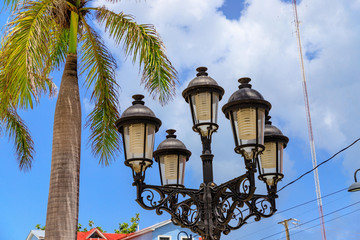 Fototapeta na wymiar Detail photo of street lamps and palm trees in the Caribbean with blue sky. Puerto Plata, Dominican Republic.