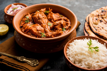 Murgh Makhani / Butter chicken tikka masala served with roti / Paratha and plain rice along with onion salad. selective focus