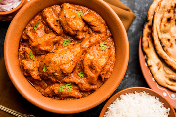 Murgh Makhani / Butter chicken tikka masala served with roti / Paratha and plain rice along with onion salad. selective focus