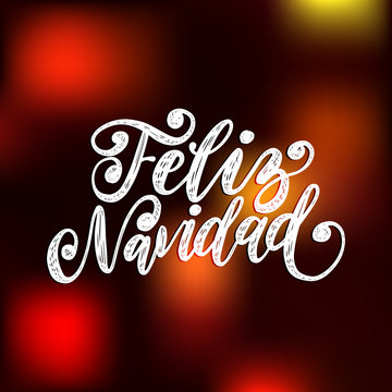 Feliz Navidad, handwritten phrase, translated from Spanish Marry Christmas on blurred background.