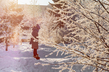 Young girl in winter park. Cold weather and sunshine. Magical winter landscape.