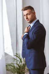 handsome man in suit wearing necktie and looking at camera