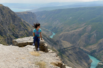 Fototapeta premium Sulak canyon in Dagestan, one of the deepest in the world. The woman enjoys the view of the canyon and the turquoise river Sulak.