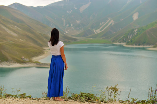 Beautiful mountain blue lake in the Chechen Republic. A young woman in a long dress on the lake.