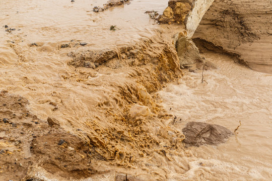 Strong storm erode the farmland, dragging the fertile surface and causing muddy floods. Detail of brown water of stream after natural disaster