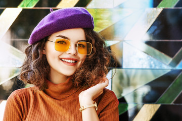 Outdoor close up portrait of beautiful fashionable happy smiling woman wearing purple beret,...