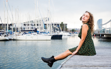 Young attractive woman tourist  sitting at quay  with sailboats on background