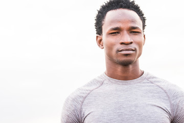 beauty male young black african afro race portrait looking at the camera standing with knowledge. sport athlete after a training outdoor with white beight sky background.