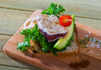 Fototapeta na wymiar Delicious pieces raw tuna, green avocado and greens at plate