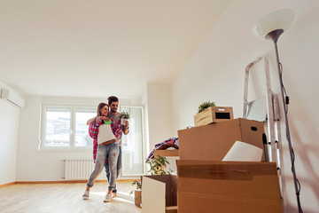 Happy young couple moving in new home unpacking boxes