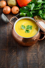 Homemade pumpkin soup in casserole on wooden background, selective focus, copy space.