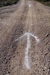 Flèche blanche dessinée sur le sol de terre