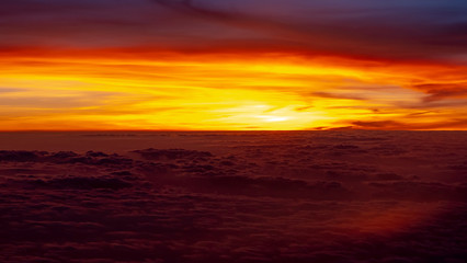 Fototapeta na wymiar Red and orange sunset over clouds as seen from an airplane