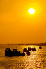 Silhouettes of small boats on Mekong river at sunset