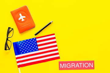 Immigration to United States of America concept. Textimmigration near passport cover and USA flag on yellow background top view
