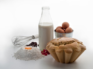 Bodegón de una botella de leche, un battidor, huevos y un bizcocho con grosellas y uvas pasas