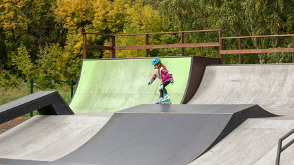 Little girl riding on roller skates in a helmet and knee pads