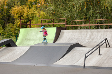 Little girl riding on roller skates in a helmet and knee pads