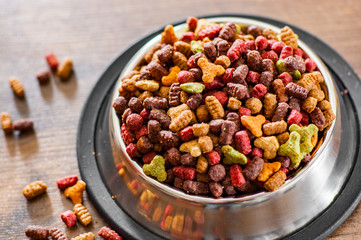 Dry Colorful cat food in metal bowl on wooden background